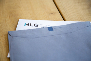Blauwe enveloppe van Belastingdienst en briefpapier van HLG accountants en adviseurs